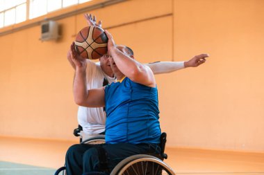 Engelli savaş gazileri ve tekerlekli sandalyeli yaş basketbol takımları spor salonunda antrenman yapıyorlar. Özürlülerin rehabilitasyonu ve kapsama konsepti