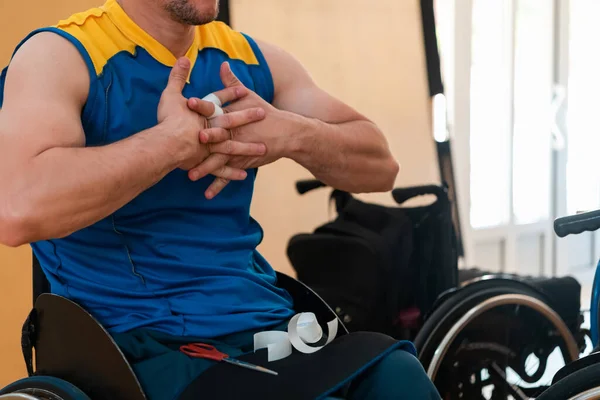 Un jugador de baloncesto discapacitado se pone un corsé y vendajes en sus brazos y dedos en preparación para un partido en la arena Fotos De Stock Sin Royalties Gratis