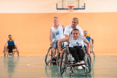 Engelli savaş gazileri ve tekerlekli sandalyeli yaş basketbol takımları spor salonunda antrenman yapıyorlar. Özürlülerin rehabilitasyonu ve kapsama konsepti