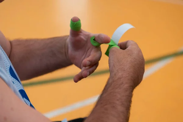 Un jugador de baloncesto discapacitado se pone un corsé y vendajes en sus brazos y dedos en preparación para un partido en la arena — Foto de Stock