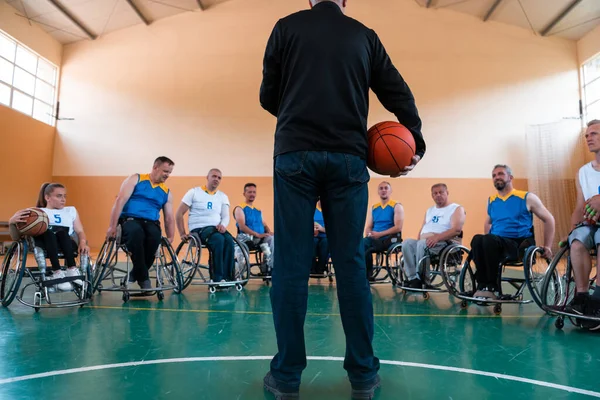 Selector Eu explico novas táticas para jogadores de basquete em cadeiras de rodas, os jogadores sentam-se em cadeiras de rodas ouvindo o seletor — Fotografia de Stock