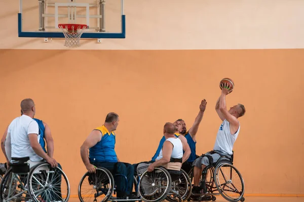 Deficientes veteranos de guerra mista raça e idade equipes de basquete em cadeiras de rodas jogando uma partida de treinamento em um ginásio de esportes salão. Conceito de reabilitação e inclusão de deficientes — Fotografia de Stock