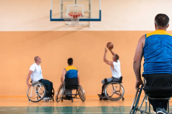 Deficientes veteranos de guerra mista raça e idade equipes de basquete em cadeiras de rodas jogando uma partida de treinamento em um ginásio de esportes salão. Conceito de reabilitação e inclusão de deficientes — Fotografia de Stock