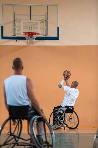 Deficientes veteranos de guerra mista raça e idade equipes de basquete em cadeiras de rodas jogando uma partida de treinamento em um ginásio de esportes salão. Conceito de reabilitação e inclusão de deficientes — Fotografia de Stock