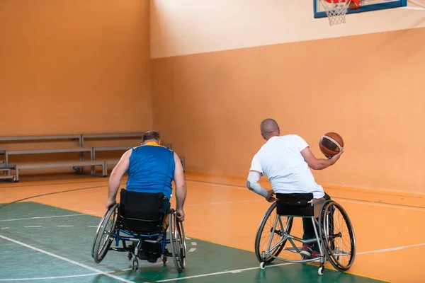 Deficientes veteranos de guerra mista raça e idade equipes de basquete em cadeiras de rodas jogando uma partida de treinamento em um ginásio de esportes salão. Conceito de reabilitação e inclusão de deficientes — Fotografia de Stock