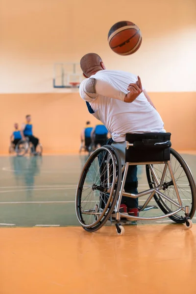 Deficientes veteranos de guerra mista raça e idade equipes de basquete em cadeiras de rodas jogando uma partida de treinamento em um ginásio de esportes salão. Conceito de reabilitação e inclusão de deficientes — Fotografia de Stock