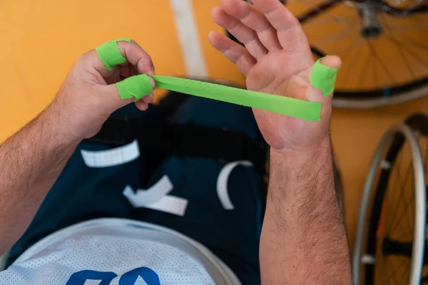 Un jugador de baloncesto discapacitado se pone un corsé y vendajes en sus brazos y dedos en preparación para un partido en la arena —  Fotos de Stock