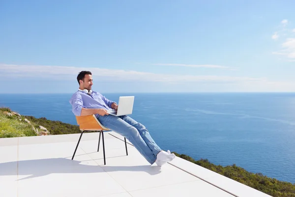 Людина на балконі з комп'ютером — стокове фото