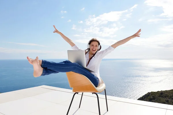 Vrouw die op laptop in hoofdtelefoon werkt — Stockfoto