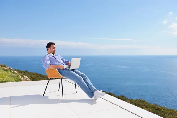 Man on balcony with computer — Stock Photo, Image