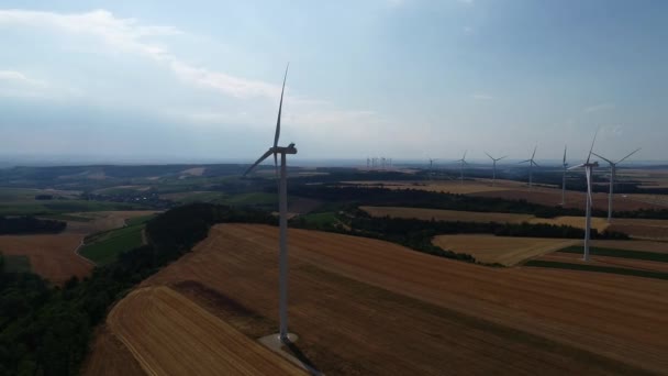 Velké větrné turbíny s lopatkami v poli letecký pohled jasně oranžová západ slunce modrá obloha větrný park zpomalení drone otáčet. Siluety větrných mlýnů, velké oranžové sluneční kotouče letní čočky. Alternativní energie — Stock video