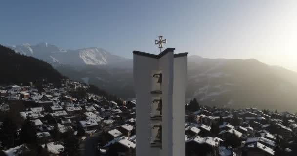 Aerial shot of a church at dawn in a beautiful Swiss village covered in snow — Stock Video
