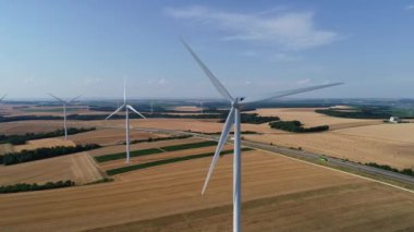 Geniş rüzgar türbinleri. Saha manzaralı, parlak turuncu günbatımı. Mavi gökyüzü parkı yavaş çekim drone dönüşü. Siluetler yel değirmenleri, büyük turuncu güneş diski yaz merceği parlamaları. Alternatif enerji