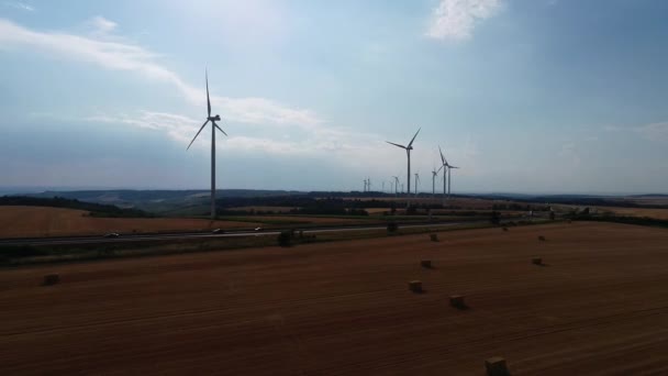 Large wind turbines with blades in field aerial view bright orange sunset blue sky wind park slow motion drone turn. Silhouettes windmills, large orange sun disc summer lens flare. Alternative energy — Stock Video