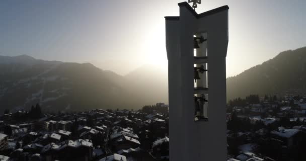 Légi felvétel egy templomról hajnalban egy gyönyörű svájci faluban, amit hó borít. — Stock videók