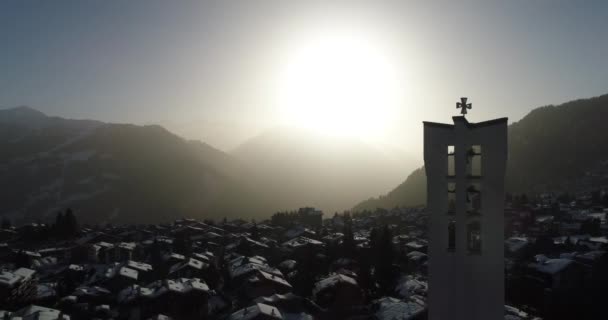 Légi felvétel egy templomról hajnalban egy gyönyörű svájci faluban, amit hó borít. — Stock videók