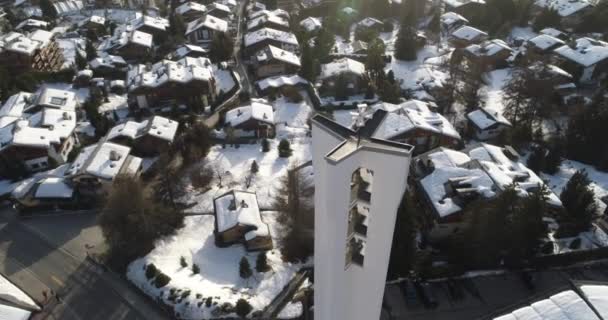 Luftaufnahme einer Kirche im Morgengrauen in einem schönen Schweizer Dorf, das mit Schnee bedeckt ist — Stockvideo
