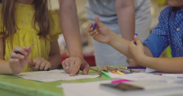 У початковій школі діти малюють в класі з вчителем-жінкою, разом граючи посміхаючись. Повільний рух — стокове відео