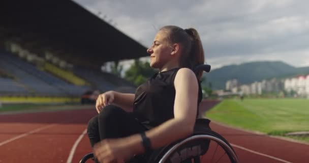 Eine behinderte Frau wärmt sich auf der Leichtathletik-Trainingsstrecke im Rollstuhl auf — Stockvideo