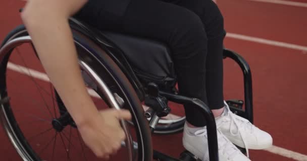 Una mujer con discapacidad montando una silla de ruedas en una pista de entrenamiento — Vídeos de Stock