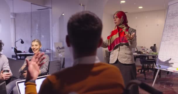 Мусульманская женщина в современном коворкинге открытого космоса выступает с презентацией для команды. Ближневосточная арабская деловая женщина в креативном офисе стартапа. Инвалид-бизнесмен в инвалидной коляске на командном собрании — стоковое видео