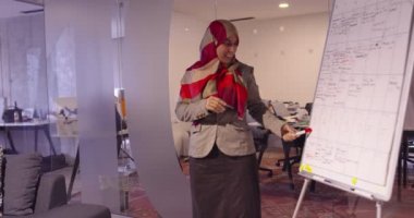 Modern bir açık alanda çalışan Müslüman bir kadın takıma bir sunum yapıyor. Orta Doğulu Arap iş kadını yaratıcı bir ofiste. Ekip toplantısında tekerlekli sandalyedeki engelli iş adamı 