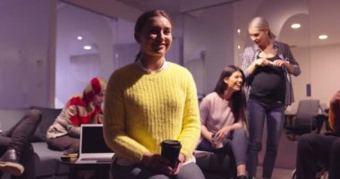 Genç bir iş kadınının, kameraya bakıp gülümseyen bir takım lideri portresi. Arka plandaki çok ırklı meslektaşlar modern açık alan başlangıç ofisindeki farklı takımlar. Yüksek kalite fotoğraf