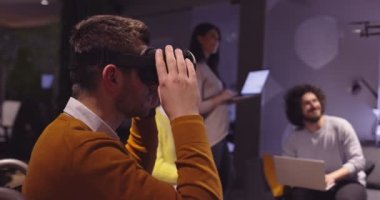 Modern açık uzay ofisinde çalışan engelli bir iş adamı sanal gerçeklik gözlüğü ve İHA simülasyonu kullanarak takım toplantısı yapıyor. Girişim işinde etkin takım çalışması.