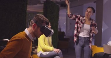 Modern açık uzay ofisinde çalışan engelli bir iş adamı sanal gerçeklik gözlüğü ve İHA simülasyonu kullanarak takım toplantısı yapıyor. Girişim işinde etkin takım çalışması.