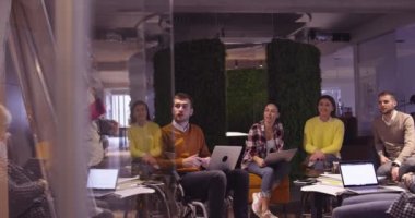 Modern bir açık alanda çalışan Müslüman bir kadın takıma bir sunum yapıyor. Orta Doğulu Arap iş kadını yaratıcı bir ofiste. Ekip toplantısında tekerlekli sandalyedeki engelli iş adamı 