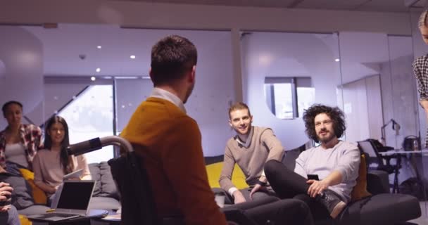 टीम मीटिंग पर आधुनिक ओपन स्पेस सहकर्मी कार्यालय में काम पर व्हीलचेयर में विकलांग व्यापारी। एक स्टार्टअप व्यवसाय में प्रभावी टीमवर्क और समावेश . — स्टॉक वीडियो
