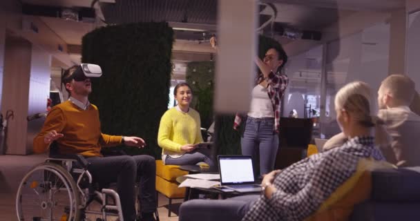 Behinderte Geschäftsleute im Rollstuhl bei der Arbeit in einem modernen Coworking-Büro im offenen Raum bei Teambesprechungen mit Virtual-Reality-Brillen und Drohnen-Simulation. Effektive Teamarbeit in einem Start-up-Unternehmen. — Stockvideo