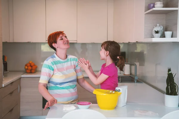 Funny niña ayudante jugando con la masa en sus manos aprendiendo a amasar ayuda a mamá adulta en la cocina, feliz linda hija bebé y mamá padre divertirse cocinando galletas. — Foto de Stock