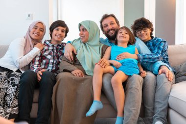 Büyük, modern bir evin oturma odasındaki koltukta oturan Arap Müslüman bir ailenin portresi. Seçici odak 