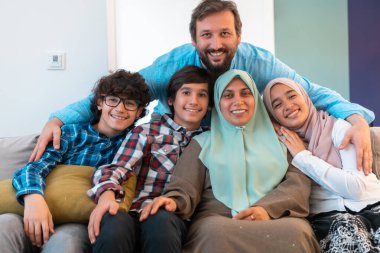 Büyük, modern bir evin oturma odasındaki koltukta oturan Arap Müslüman bir ailenin portresi. Seçici odak 