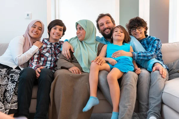 Foto de retrato de una familia árabe musulmana sentada en un sofá en la sala de estar de una gran casa moderna. Enfoque selectivo —  Fotos de Stock