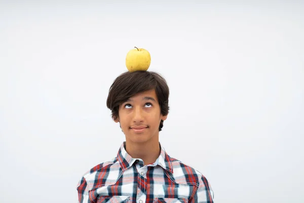 Un retrato divertido de un joven y atractivo chico árabe con manzana en la cabeza aislada sobre un fondo blanco. Enfoque selectivo — Foto de Stock