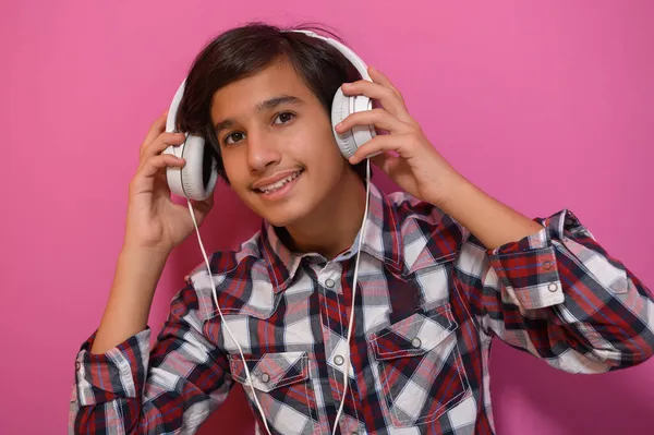 Arabisch tiener jongen dragen hoofdtelefoon en luisteren naar muziek roze achtergrond — Stockfoto
