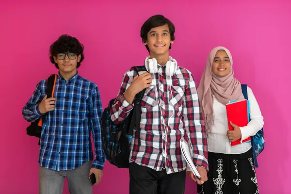 Eine Gruppe arabischer Teenager, ein Studententeam, das in die Zukunft und zurück in die Schule geht, das Konzept eines rosafarbenen Hintergrunds. Das Konzept erfolgreicher Bildung für junge Menschen. Selektiver Fokus Stockbild