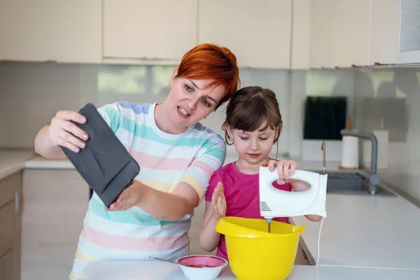 Liten flicka och mamma gör tastz tårta i kithen familj att ha kul hemma — Stockfoto