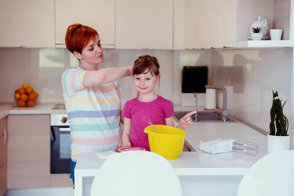 Grappig klein meisje helper spelen met deeg op zijn handen leren kneden helpt volwassen moeder in de keuken, gelukkig schattig dochtertje en ouder moeder veel plezier koken koekjes. — Stockfoto