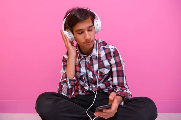 阿拉伯少年头戴耳机，听音乐粉色背景 — 图库照片