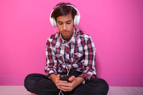 Arabisch tiener jongen dragen hoofdtelefoon en luisteren naar muziek roze achtergrond — Stockfoto
