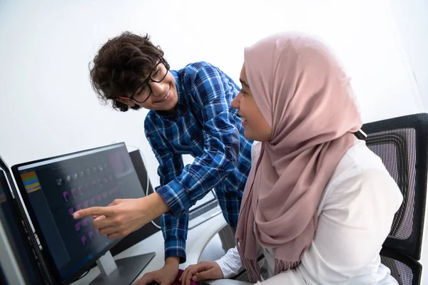 Start-up-Unternehmen, junge Kreative diskutieren über Treffen im hellen Büro, während sie auf einen Dual-Monitor-Computer für Vorschläge und Hilfe im Projekt zeigen — Stockfoto