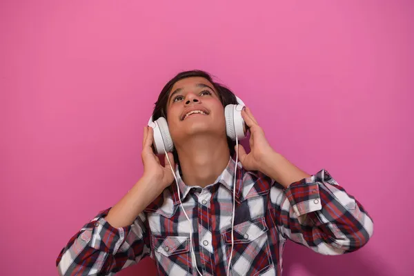 Árabe adolescente menino vestindo fones de ouvido e ouvir música rosa fundo — Fotografia de Stock