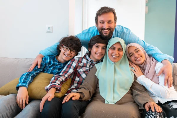 Foto de retrato de una familia árabe musulmana sentada en un sofá en la sala de estar de una gran casa moderna. Enfoque selectivo —  Fotos de Stock