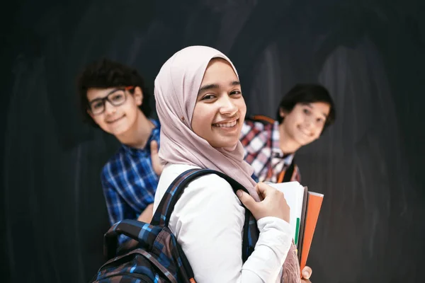 Arabische tieners, studenten groepsportret tegen zwart schoolbord met rugzak en boeken op school.Selectieve focus — Stockfoto