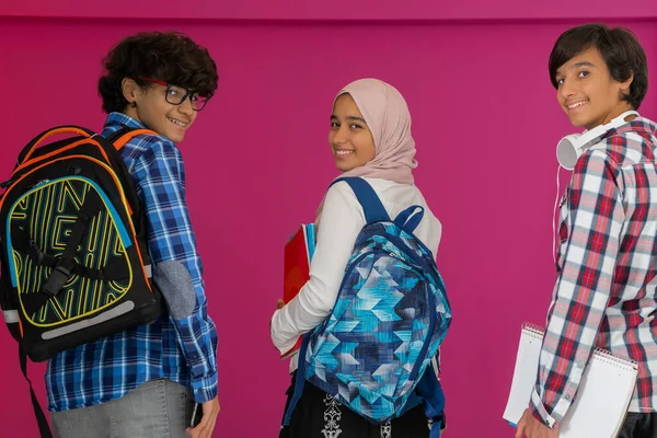 Un groupe d'adolescents arabes, une équipe d'étudiants marchant vers l'avenir et retournant à l'école le concept d'un fond rose. Le concept d'une éducation réussie pour les jeunes. Concentration sélective — Photo