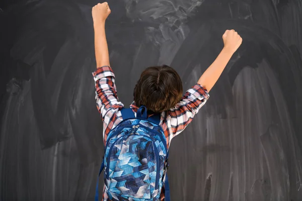 Garçon célèbre une école réussie avec ses mains en l'air comme il fait face au tableau noir de l'école — Photo