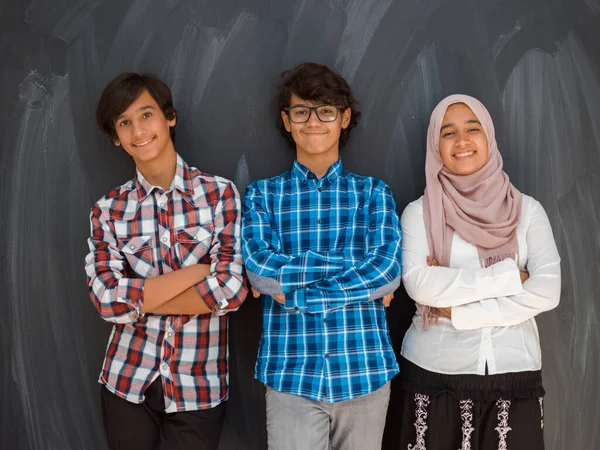 Ett porträtt av en grupp arabiska tonåringar med korsade armar som står framför en skolstyrelse. Begreppet modern och framgångsrik utbildning — Stockfoto